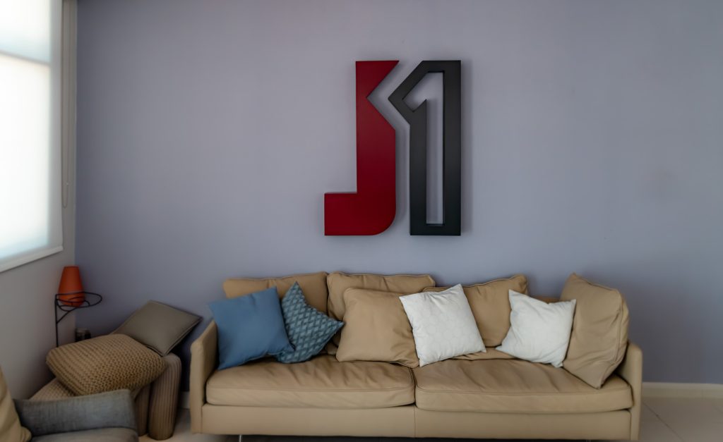 A photo showing is so far along with some throw pillows in front of a wall, showing the logo of the warehouse brand.
